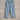 Light blue Cowrie flowers lounge embroidered linen pants against a wall