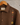 Close up of brown jacket with zari flower motif displayed against the wall.