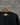 Black pashmina tshirt closeup displayed against grey brick wall 